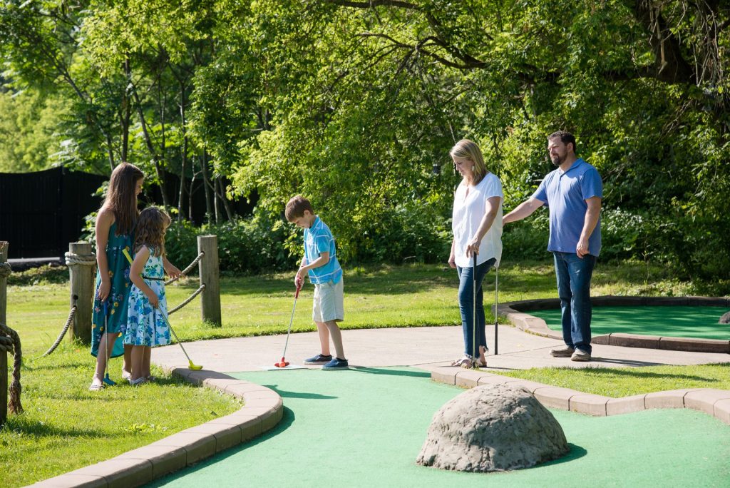 Family playing miniature golf at Barnyard Swing in Cooperstown, NY